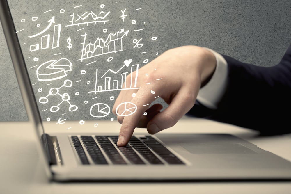 Sales person in suit using a laptop to calculate pie chart and exponential growth statistics on office desk concept